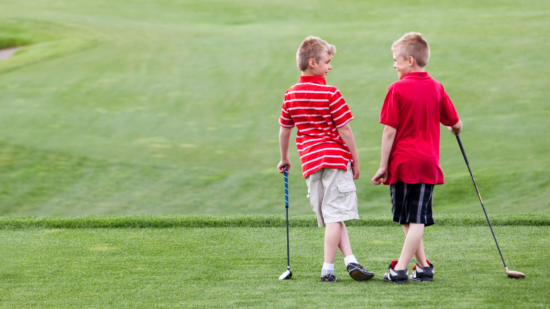 two kids on the driving range golfing