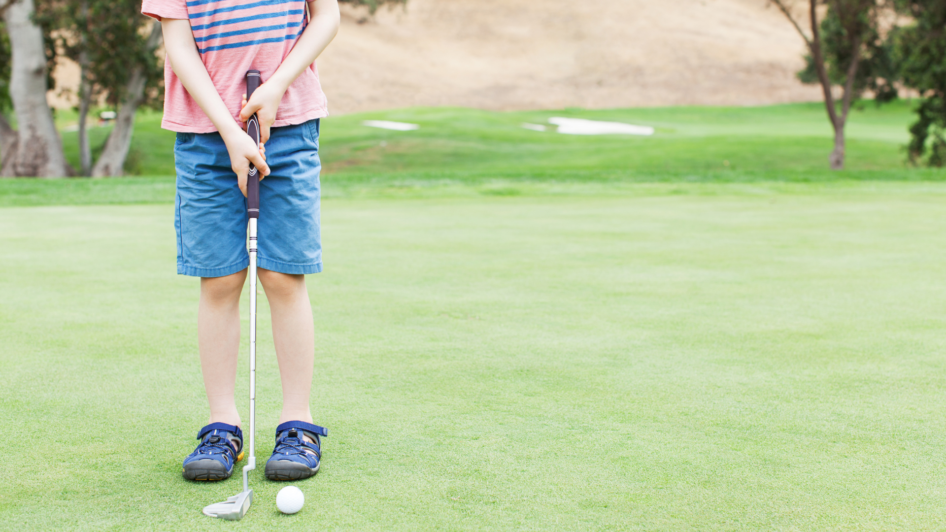 child holding putter on the green