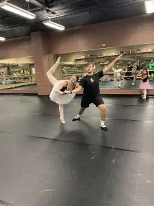 a woman in a ballet costume and a man dancing in the dance studio as a child watches
