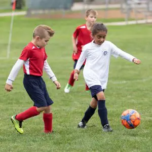 two kids playing socce on soccer field