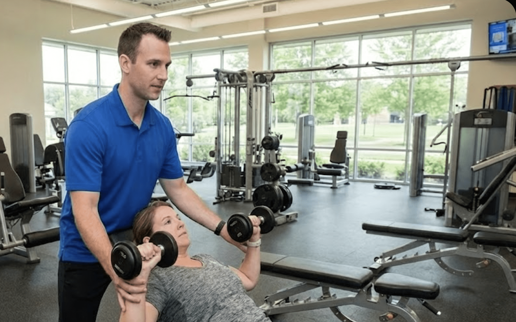 a person helping a person lifting weights