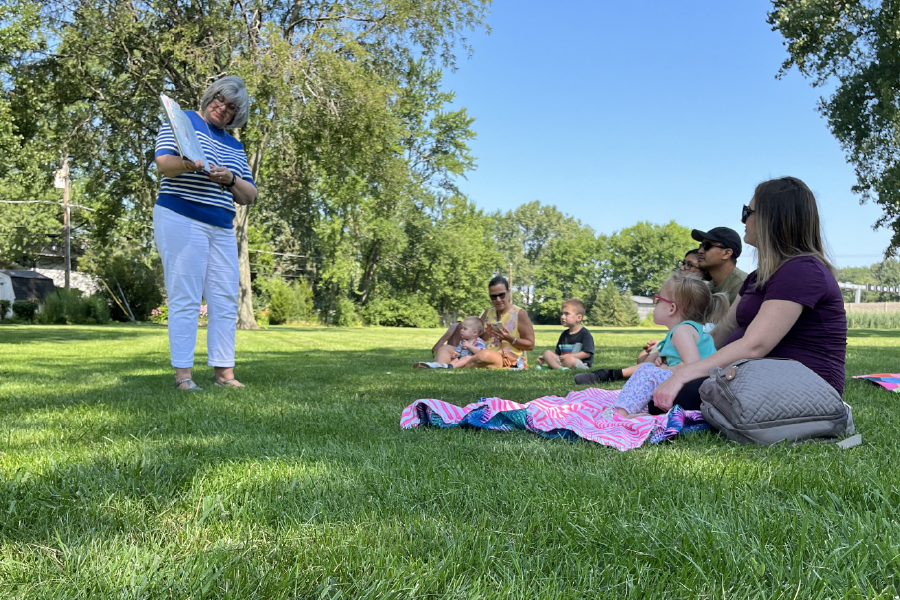 a person standing in a grassy area with a group of people sitting on blankets