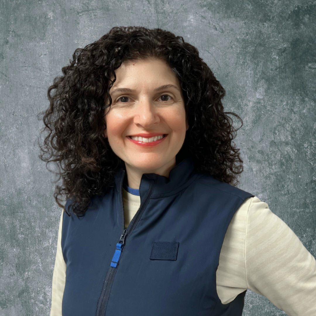 a person with curly hair wearing a vest