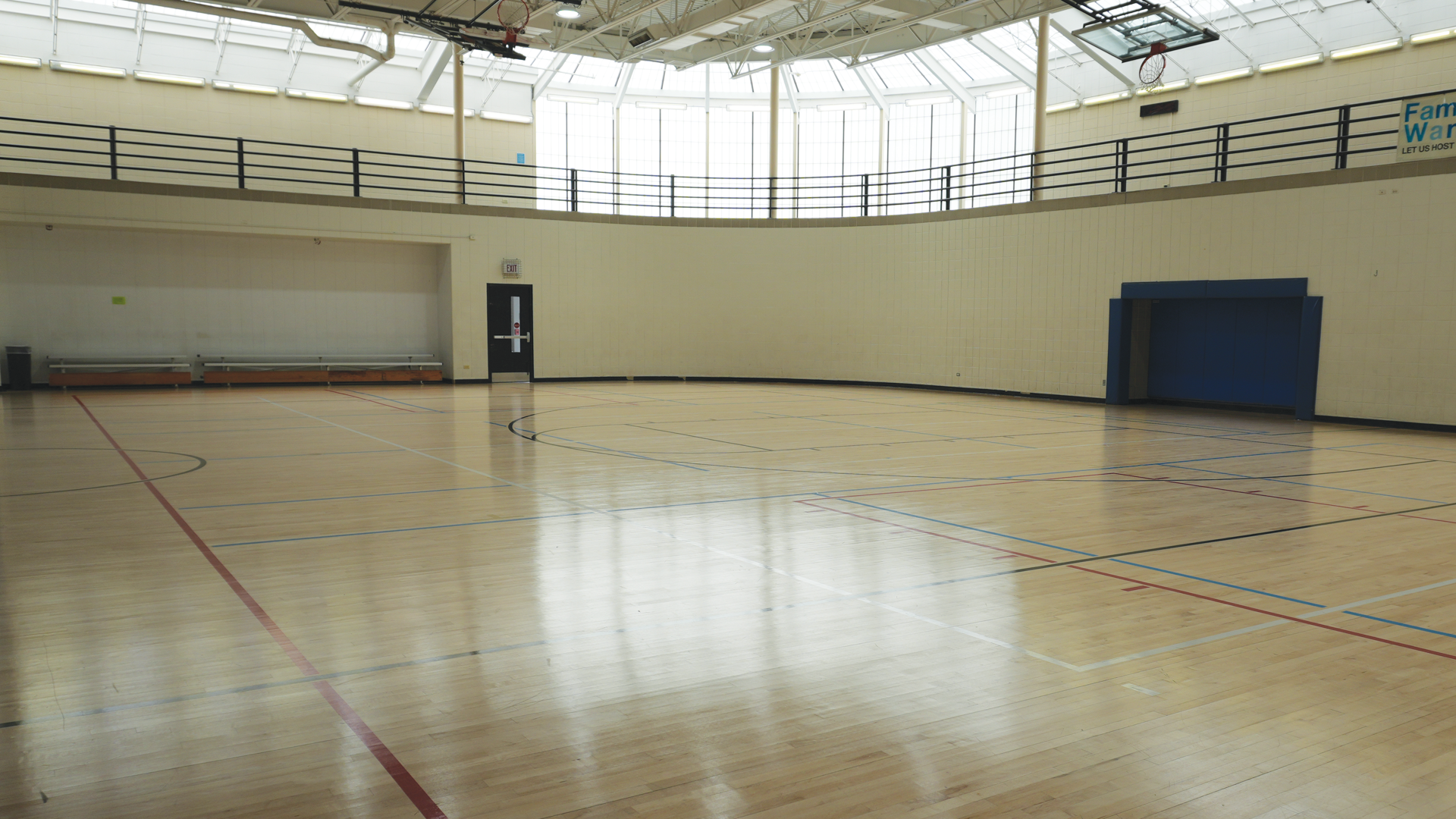 a gym with a basketball court and a white wall
